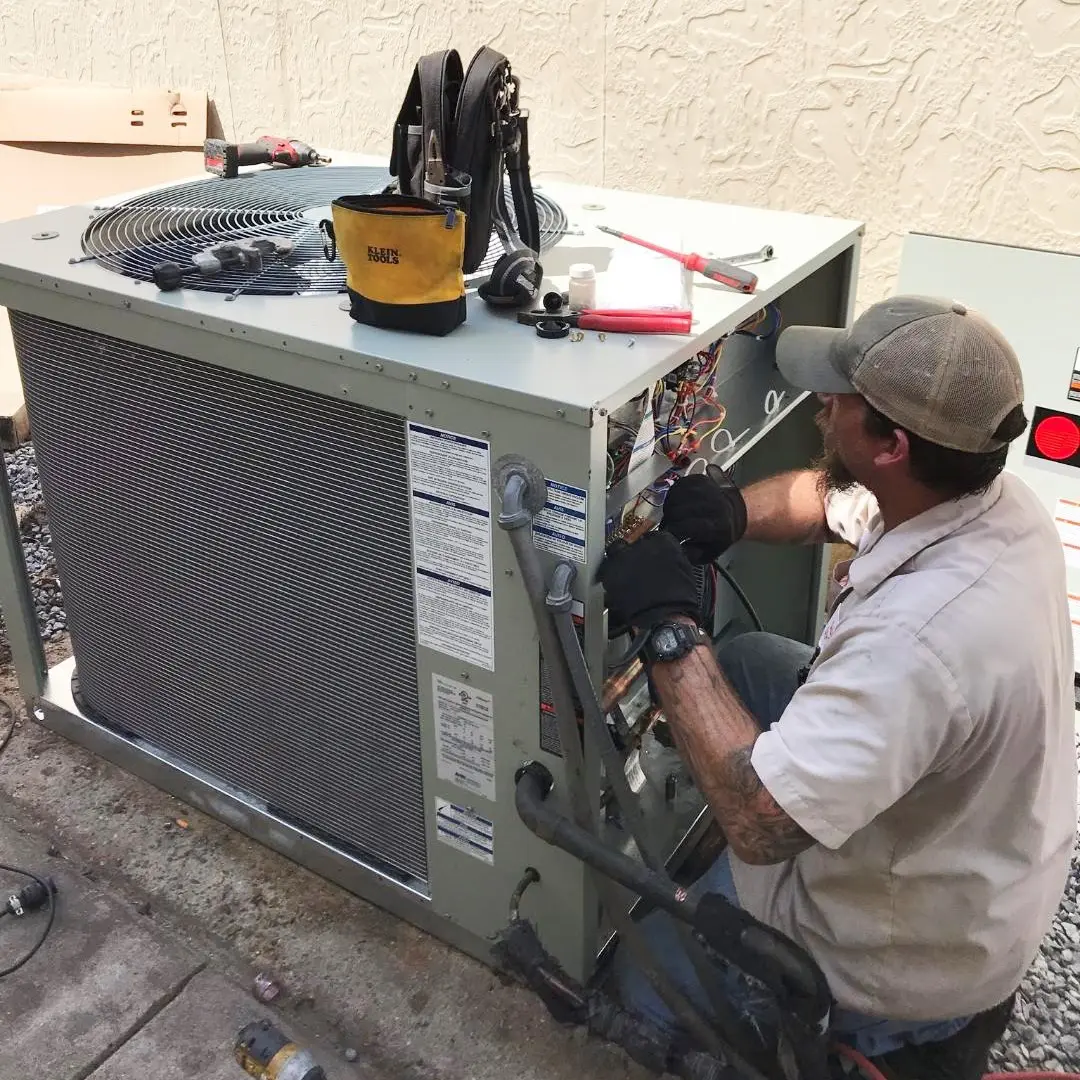 Technician inspecting an older residential air conditioner unit Technician inspecting an older residential air conditioner unit